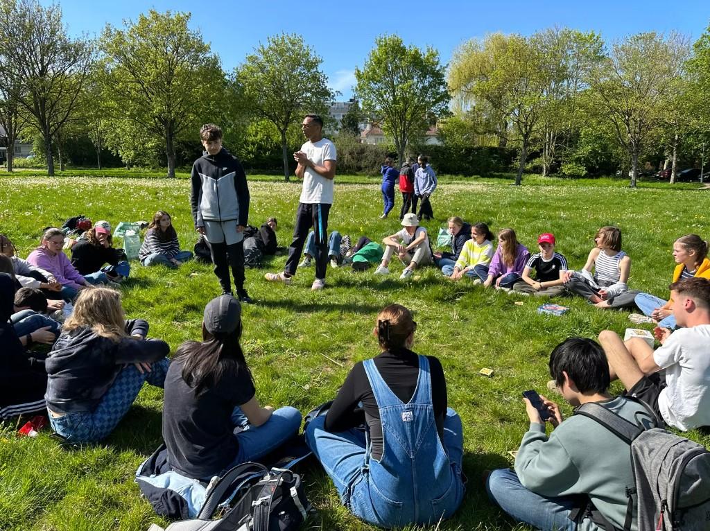 Leerlingen zitten in een cirkel tijdens een buitenworkshop in het park