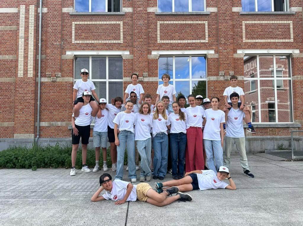 Groep leerlingen poseert samen voor een schoolgebouw tijdens een schooluitstap