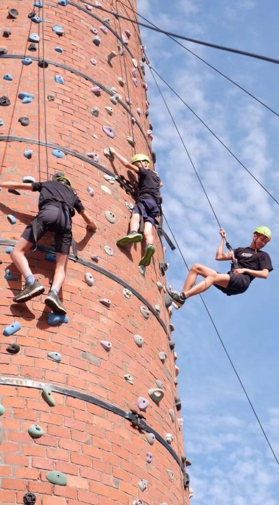 Leerlingen klimmen op een klimtoren tijdens een schooluitstap