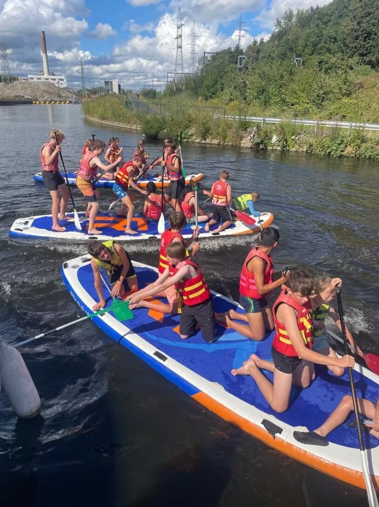 Leerlingen op grote supboards tijdens een schooluitstap op het water