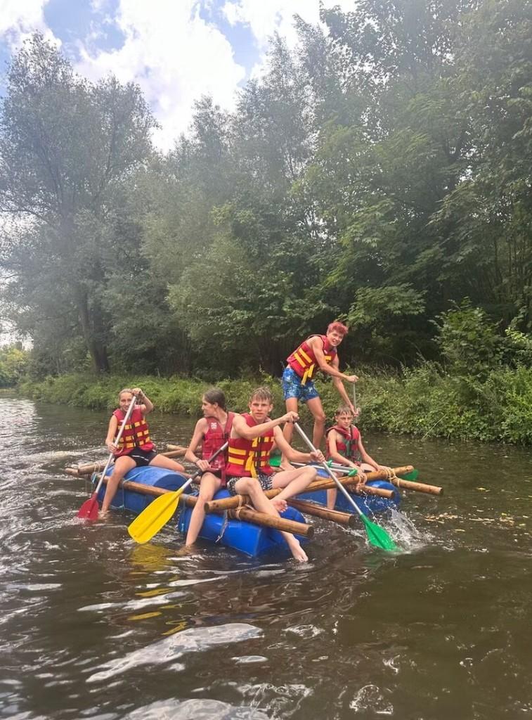 Leerlingen peddelen op een zelfgebouwd vlot tijdens een outdooractiviteit